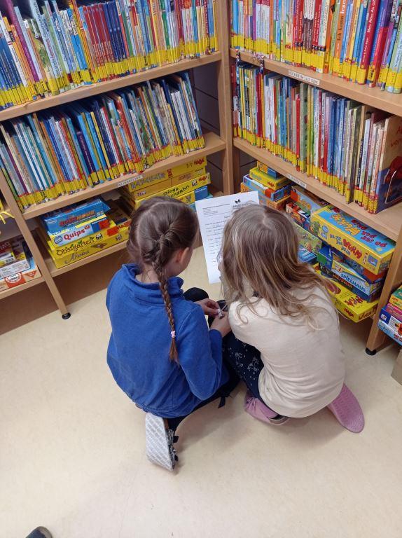 Lesende Mädchen vor Bücherregalen